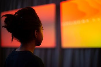 Woman looking at orange coloured screens as part of the Dreamachine experience