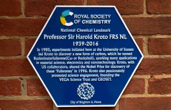 A close up of a hexagonal blue plaque against a red brick background. The plaque reads: Royal Society of Chemistry National Chemistry Landmark. Professor Sir Harold Kroto FRS NL 1939-2016.