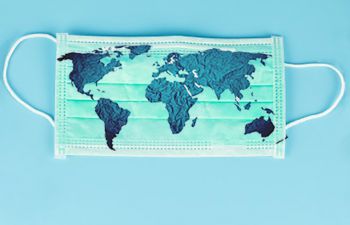 A surgical facemask on a blue background with a map of different countries on top of the mask