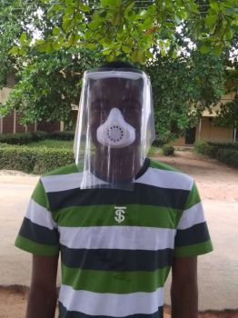 A researcher in Nigeria wearing a striped top wears a surgical mask printed by a 3D printer