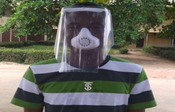 A researcher in Nigeria wearing a striped top wears a surgical mask printed by a 3D printer