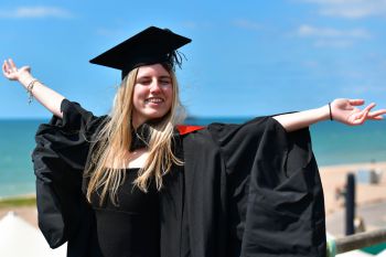 A female graduate celebrated getting her degree by raising her arms