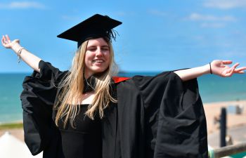 A female graduate celebrated getting her degree by raising her arms