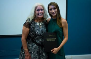 Two women holding a bound book as prize dissertation award