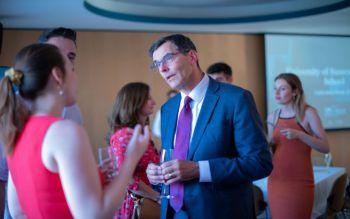 Man standing with drink talking to event guests