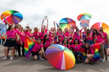 A group wearing University of Sussex-branded pink T-Shirts gathers at the start of Pride 2019