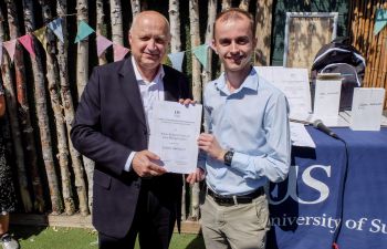 James Akehurst pictured at a recent graduation party accepting the Brian John Roberts prize, which they also won. James stands next to head of the engineering department Romeo Glovnea and hold a certificate between them.