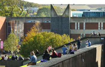 Campus shot of the University of Sussex, students outside the library