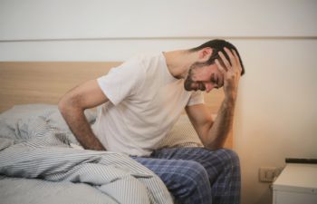A young man can't get up from bed due to a terrible headache