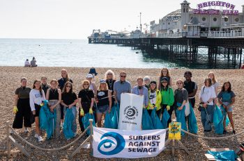 Students at welcome week 2021 stand with litter pickers and Surfers against sewage bags, in front of Palace Pier