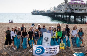 Students at welcome week 2021 stand with litter pickers and Surfers against sewage bags, in front of Palace Pier