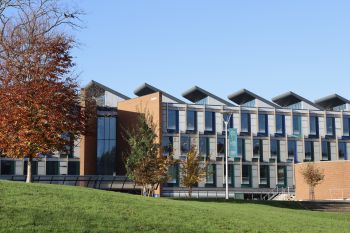 Exterior of Jubilee Building, University of Sussex Business School, with trees and blue sky