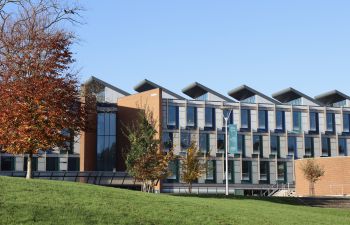 Exterior of Jubilee Building, University of Sussex Business School, with trees and blue sky