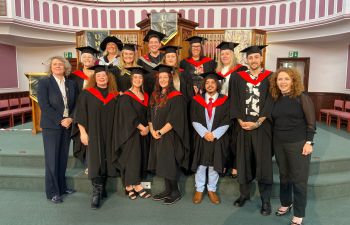 Social Work BA graduates and their Jersey course tutors following their graduation ceremony in a formal setting