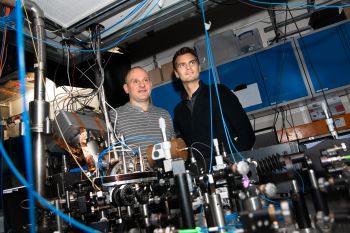 Founders of Sussex spin-out, Universal Quantum, Prof Winfried Hensinger and Dr Sebastian Weidt, standing behind the quantum computer that they built in their Sussex laboratory