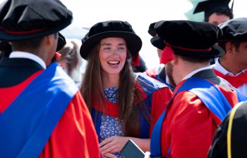 A smiling Rosemary Coogan is dressed in graduation mortar board and gown on a sunny day