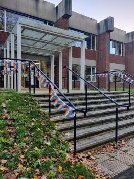 Picture of the doors of Chichester I, with progress flag bunting wrapped around the railings and a large progress flag on a pole.