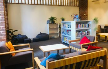 The Library Wellbeing Collection area with hundreds of print books and comfortable seating.
