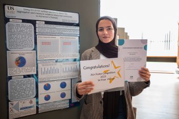 JRA competition winner Dana Aljarrah with her certificate and poster on using SH-SY5Y cortical neurons to detect Tau aggregation and measure oxidative stress that contributes to Alzheimer's disease.