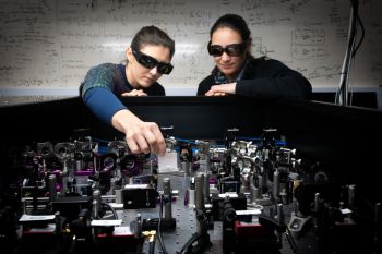 Two scientists wearing black goggles aligning laser lines in the Quantum Physics laboratory at the University of Sussex