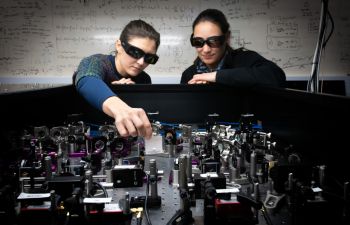 Two scientists wearing black goggles aligning laser lines in the Quantum Physics laboratory at the University of Sussex