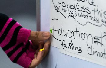 A student votes for their favourite ideas for reducing meat demand on campus, by sticking a star shaped sticker next to the title saying 