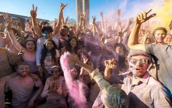 Crowd covered in colours smiling at the camera during Holi 2017