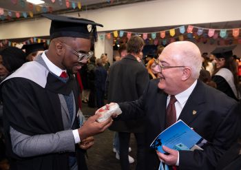 Man giving male graduate a gift