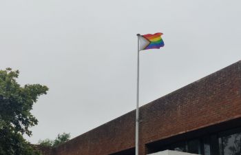 The rainbow progress pride flag flying over Sussex House on a cloudy day