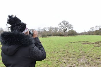 Student looking through binoculars to spot birds at Knepp Estate