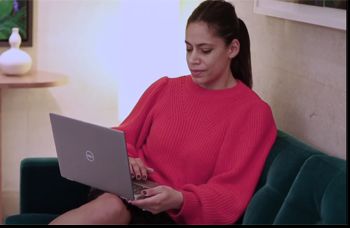 Woman sat in a sofa studying an online Masters with her laptop