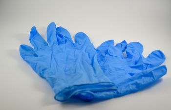 A pair of blue disposable gloves used for surgical procedures close up on a neutral background