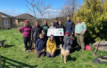 A group of volunteers and Sussex researchers installing and presenting the new pollinator signs, guides and bee hotels