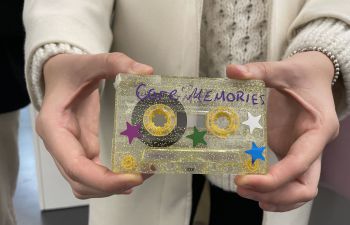 Person holding a cassette tape covered in glitter and stars with the text 
