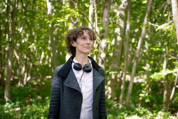 Alice Eldridge wearing headphones around her neck standing amongst trees