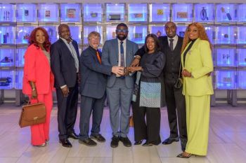 7 people stood celebrating the success of NIGCOSAT at the IET.