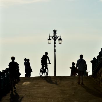 Silhouette of a cyclist on Brighton seafront, with pedestrians around them.