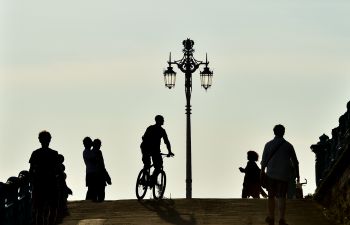 Silhouette of a cyclist on Brighton seafront, with pedestrians around them.