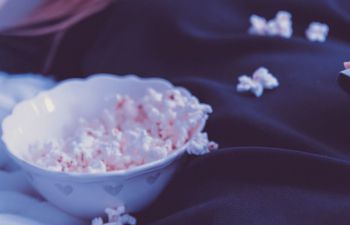 Woman eating popcorn smiling with popcorn and TV remote in foreground