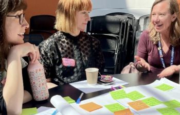 Three members of staff collaborating with post-its notes in a sunlit room