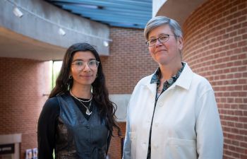 2 people facing forwards, standing side by side smiling, in the ACCA building. On the left Nabihah Iqbal, on the right VC Prof. Sasha Roseneil