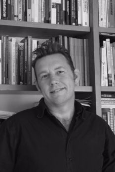 Black and white image of Professor Peter Newell in his office