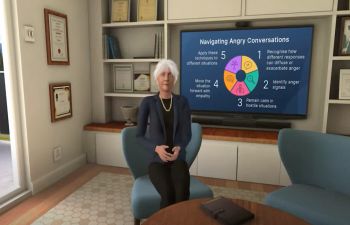 An avatar of Dame Lesley Fallowfield showing her sat in an office setting in front of a screen