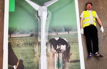 photograph of Micheal dressed in high vis lying down next to a windmill packaged up with batteries