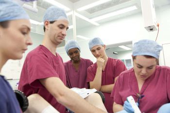 A group of students in theatre wearing pink scrubs