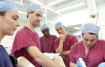 A group of students in theatre wearing pink scrubs