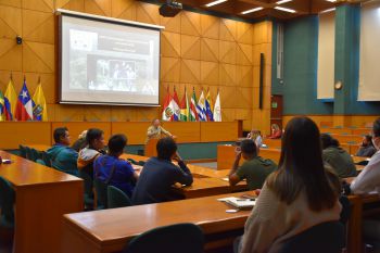 Professor Mika Peck giving a talk at in a big auditorium.