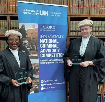 Students standing with award in front of Oxford University banner