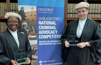 Students standing with award in front of Oxford University banner