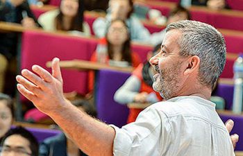 Person standing in the front of a large lecture theatre, teaching students